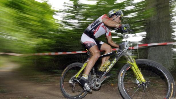 Ein Mountainbiker fährt schnell auf einer unbefestigten Strecke durch den Wald.