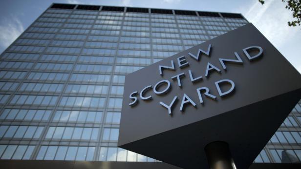Das Schild „New Scotland Yard“ vor einem modernen Bürogebäude.