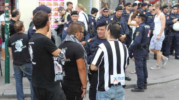 Eine Gruppe von Männern steht auf der Straße, umgeben von Polizisten.