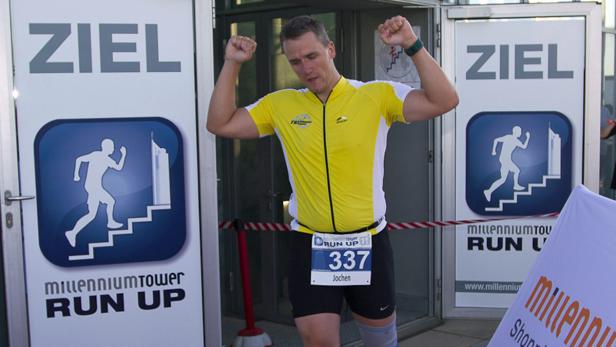 Jochen überquert die Ziellinie beim Millennium Tower Run Up mit erhobenen Armen.