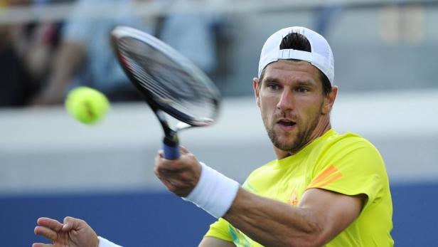 Ein Tennisspieler schlägt einen Tennisball mit seinem Schläger.