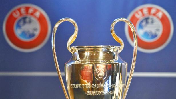 Nahaufnahme des UEFA Champions League Pokals vor blauem Hintergrund.
