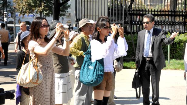 Eine Reisegruppe mit einem asiatischen Reiseleiter besichtigt eine Stadt.