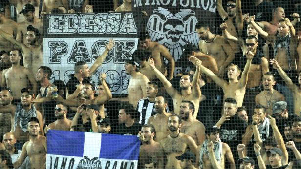 Eine Gruppe von Fans feuert ihr Team hinter einem Zaun an.