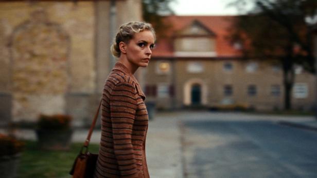 Eine Frau mit geflochtenem Haar blickt über ihre Schulter auf einer Straße.