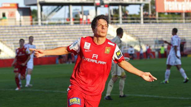 Ein Fußballspieler in rotem Trikot jubelt auf dem Spielfeld.