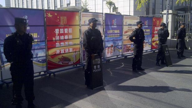 Chinesische Polizisten stehen vor Bannern mit chinesischen Schriftzeichen.