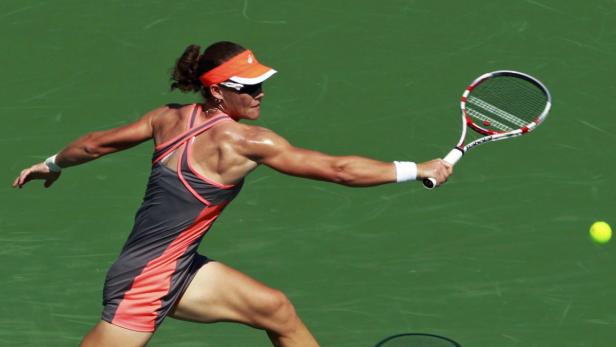 Eine Tennisspielerin schlägt einen Ball mit ihrem Schläger.