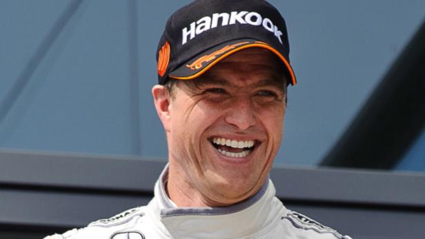 Michael Schumacher lächelt in die Kamera und trägt eine Hankook-Kappe.