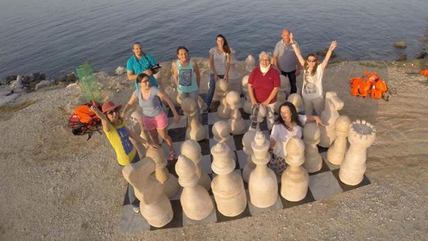 Eine Gruppe von Menschen posiert auf einem riesigen Schachbrett am Ufer.