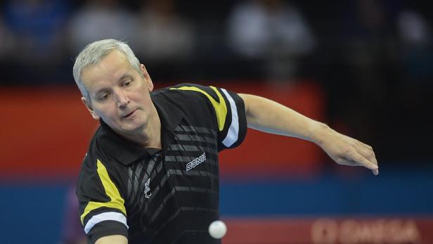 Ein Mann mit grauem Haar spielt Tischtennis.