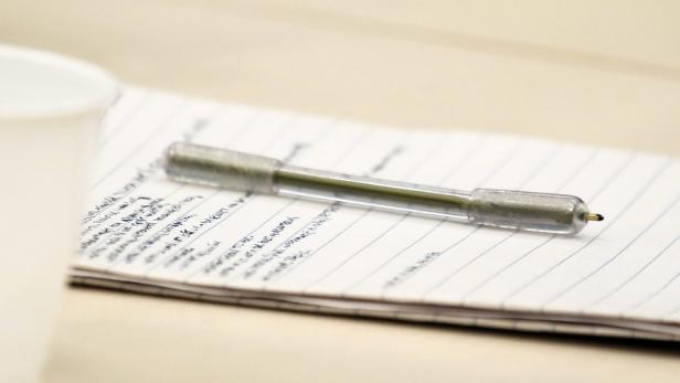 Ein Stift liegt auf einem Notizblock mit linierten Seiten.