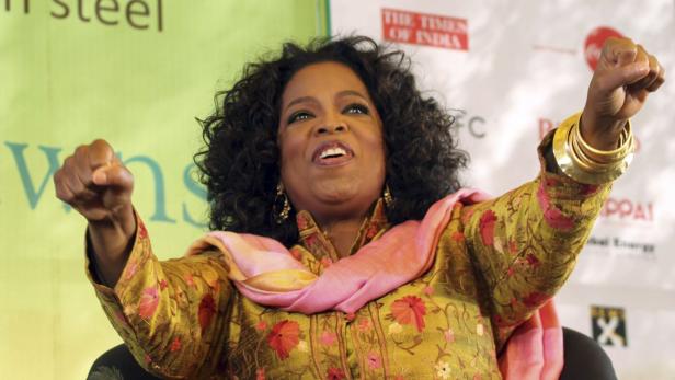 Oprah Winfrey mit erhobenen Fäusten bei einer Veranstaltung.