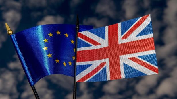 Die Flaggen der Europäischen Union und des Vereinigten Königreichs vor einem bewölkten Himmel.