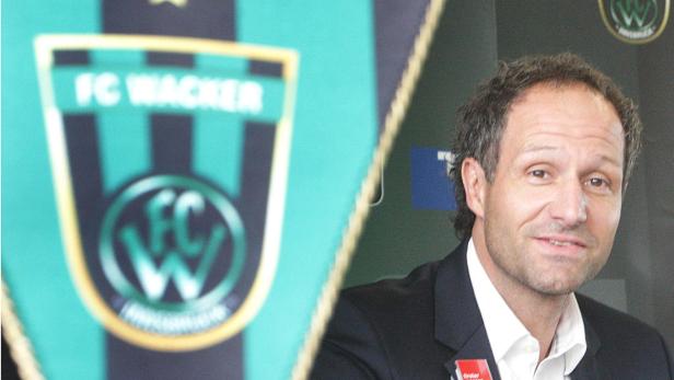 Ein Mann steht neben einem Wimpel des FC Wacker Innsbruck.