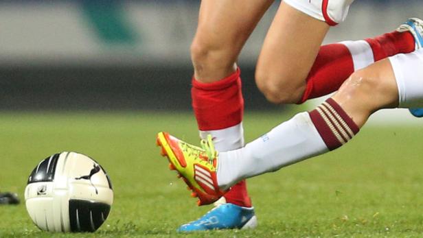 Zwei Fußballspielerinnen kämpfen um den Ball auf dem Spielfeld.