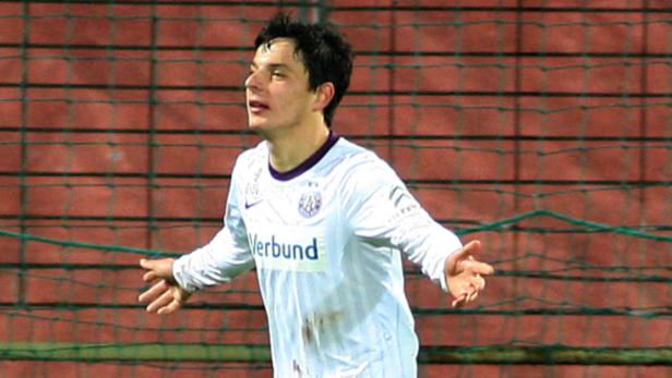 Ein Fußballspieler in weißem Trikot mit dem Schriftzug „Verbund“ jubelt.