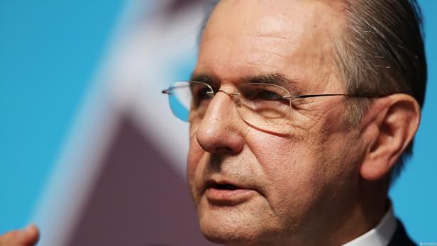 Ein Mann mit Brille spricht vor einem blauen Hintergrund.