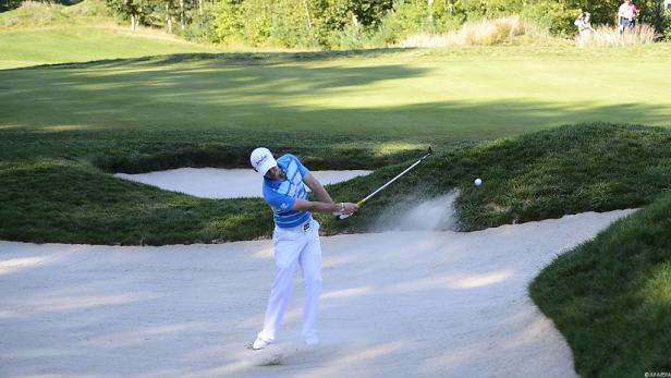 Ein Golfspieler schlägt einen Ball aus einem Sandbunker.