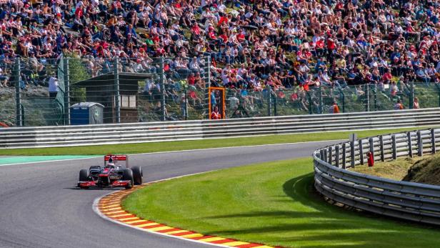 Ein Formel-1-Rennwagen fährt auf einer Rennstrecke vor einer Zuschauermenge.