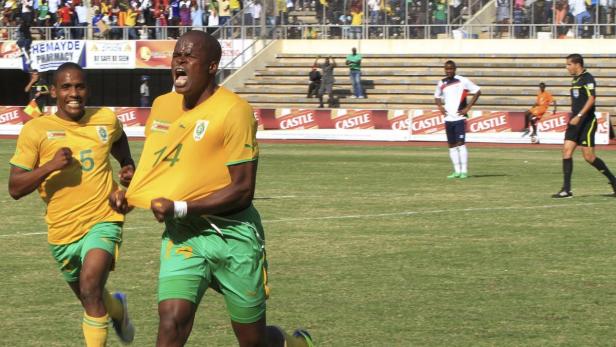 Zwei Fußballspieler in gelb-grünen Trikots jubeln auf dem Spielfeld.