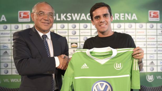 Ein Fußballspieler des VfL Wolfsburg hält sein neues Trikot bei der Vertragsunterzeichnung.