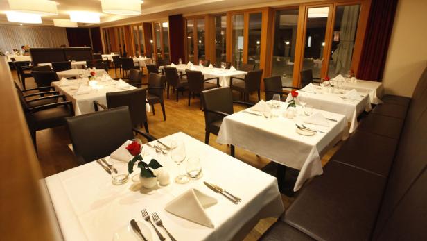 Ein elegant gedeckter Tisch in einem Restaurant mit weißen Tischdecken und roten Rosen.