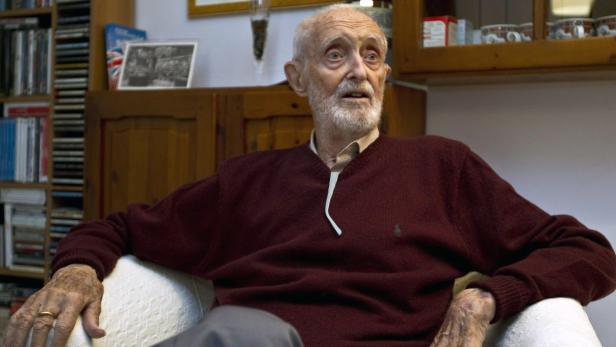 Ein älterer Mann mit Bart sitzt in einem Sessel.