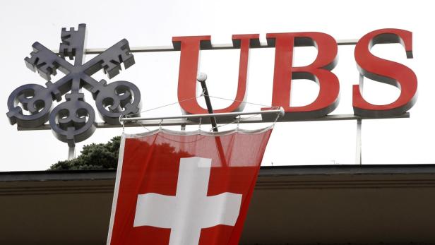 Das UBS-Logo mit dem Schweizerkreuz auf einer roten Flagge vor einem Gebäude.
