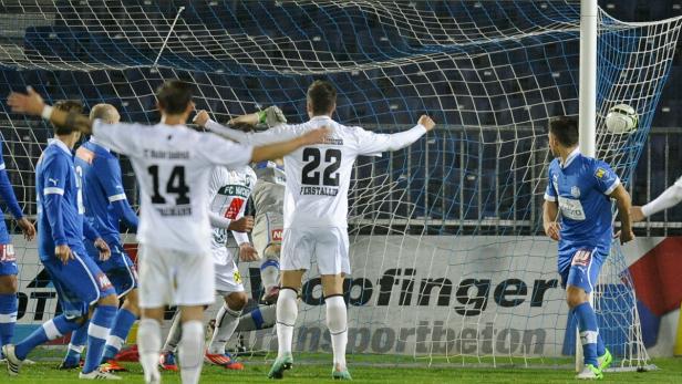 Fußballspieler jubeln nach einem Torerfolg vor dem Netz.