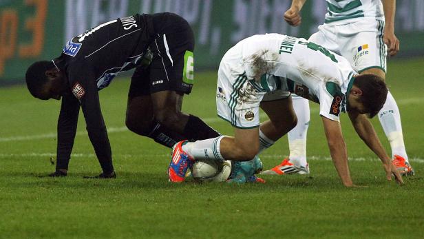 Zwei Fußballspieler kämpfen um den Ball auf dem Rasen.