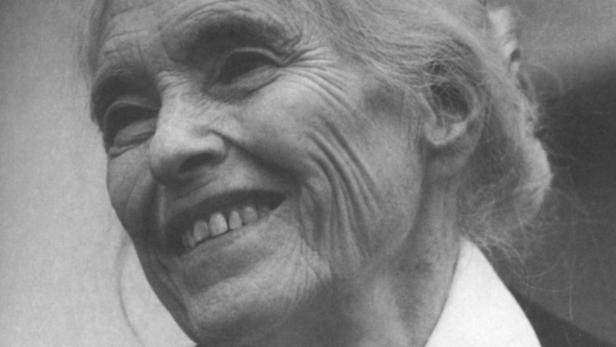 Nahaufnahme einer lächelnden älteren Frau in Schwarzweiß.