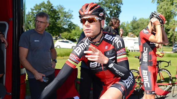 Ein Radfahrer in roter und schwarzer Rennbekleidung steht im Freien.
