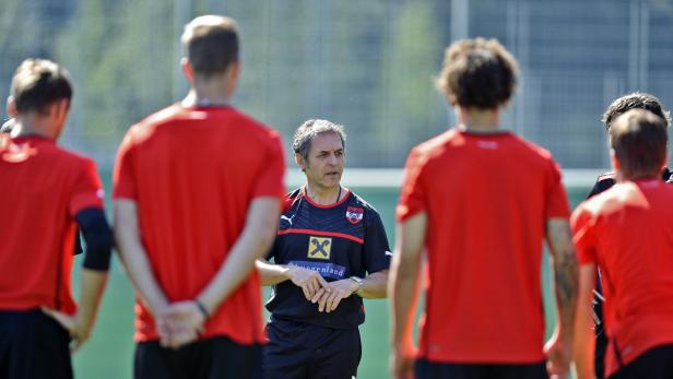 Der Trainer spricht zu einer Gruppe von Fußballspielern in roten Trikots.