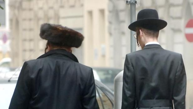 Zwei orthodoxe Juden gehen eine Straße entlang.