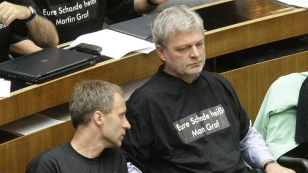 Zwei Männer tragen T-Shirts mit der Aufschrift „Eure Schande heißt Martin Graf“.
