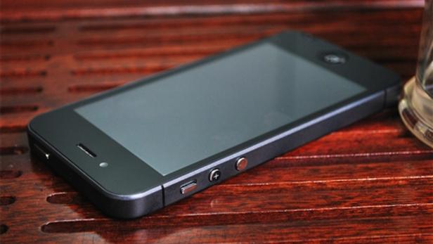 Ein schwarzes Smartphone liegt auf einer braunen Holzoberfläche.