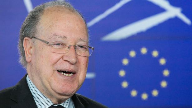 Ein älterer Mann mit Brille lächelt vor dem Hintergrund der Europaflagge.