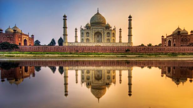 Das Taj Mahal spiegelt sich im Wasser bei Sonnenaufgang.