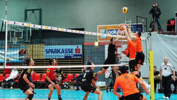 Volleyballspieler springen am Netz, um den Ball zu blocken.