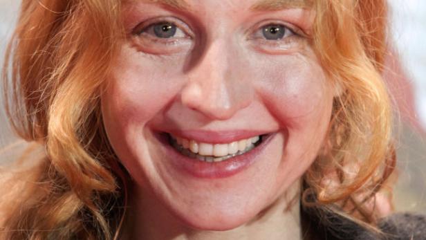 Eine lächelnde Frau mit roten Haaren und hellem Teint.