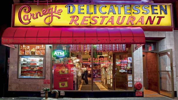 Die Fassade des Carnegie Delicatessen Restaurant mit roter Markise und Neonreklame.