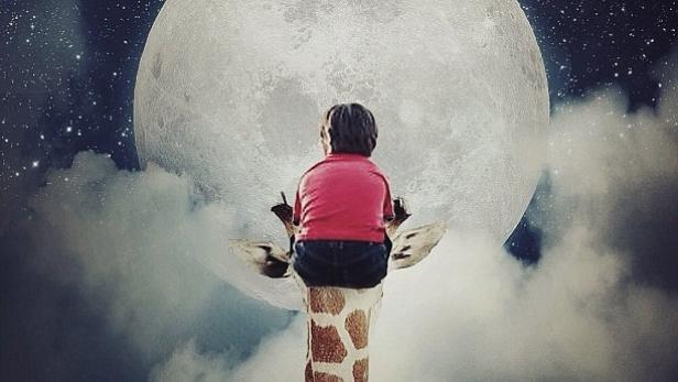 Ein Kind sitzt auf dem Kopf einer Giraffe und blickt zum Mond auf einem sternenklaren Nachthimmel.