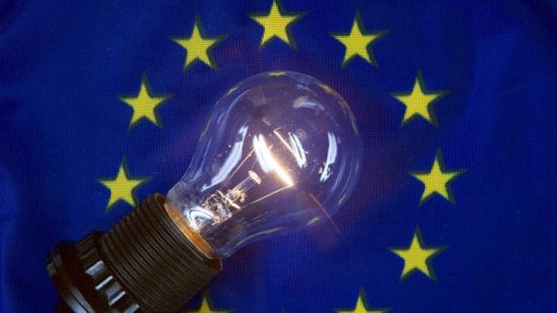 Eine Glühbirne leuchtet vor der Europaflagge.