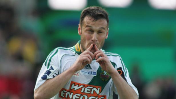 Ein Fußballspieler in einem weißen Trikot mit grünem Aufdruck jubelt.