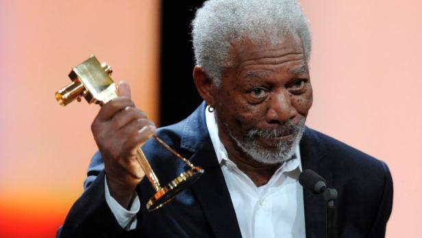 Morgan Freeman hält eine goldene Auszeichnung in der Hand.