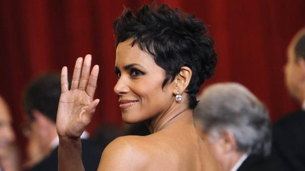 Halle Berry winkt mit erhobener Hand in die Kamera.