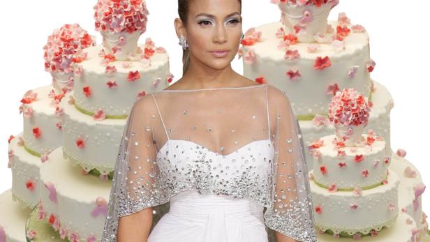 Jennifer Lopez in einem weißen Kleid vor mehreren Hochzeitstorten.