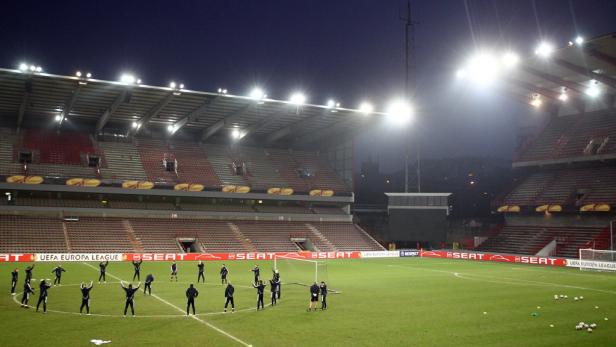 Fußballspieler wärmen sich vor einem Spiel in einem leeren Stadion auf.
