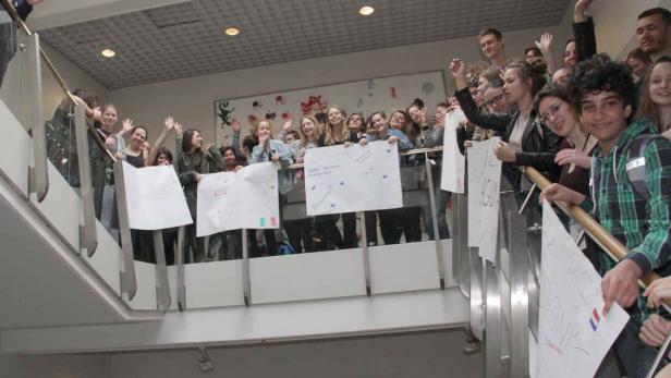 Die Jugendlichen des Erasmus-Plus-Projekts &quot;Increase&quot; versammeln sich am letzten Tag im Schulhaus und halten vielsprachige Plakate ins Stiegenhaus